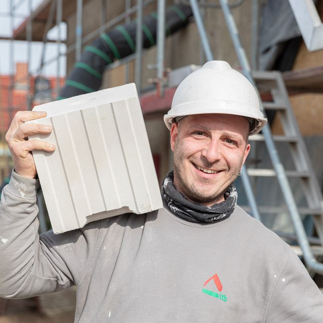 Bauhandwerker mit Blockziegel bei der Sanierung eines Mehrfamilienhauses