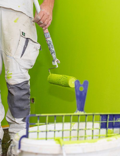 frisches Apfelgrün - Renovierungs- und, Malerarbeiten mit Malerrolle, Farbeimer und grüner Wand