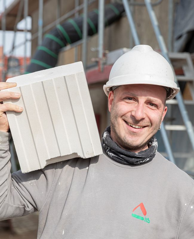Bauhandwerker mit Blockziegel bei der Sanierung eines Mehrfamilienhauses