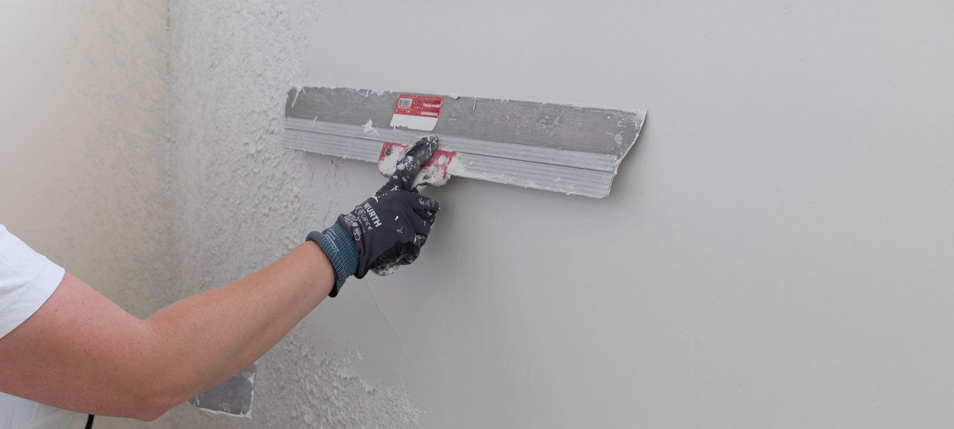 Handwerkerin beim verspachteln und glätten einer Wand